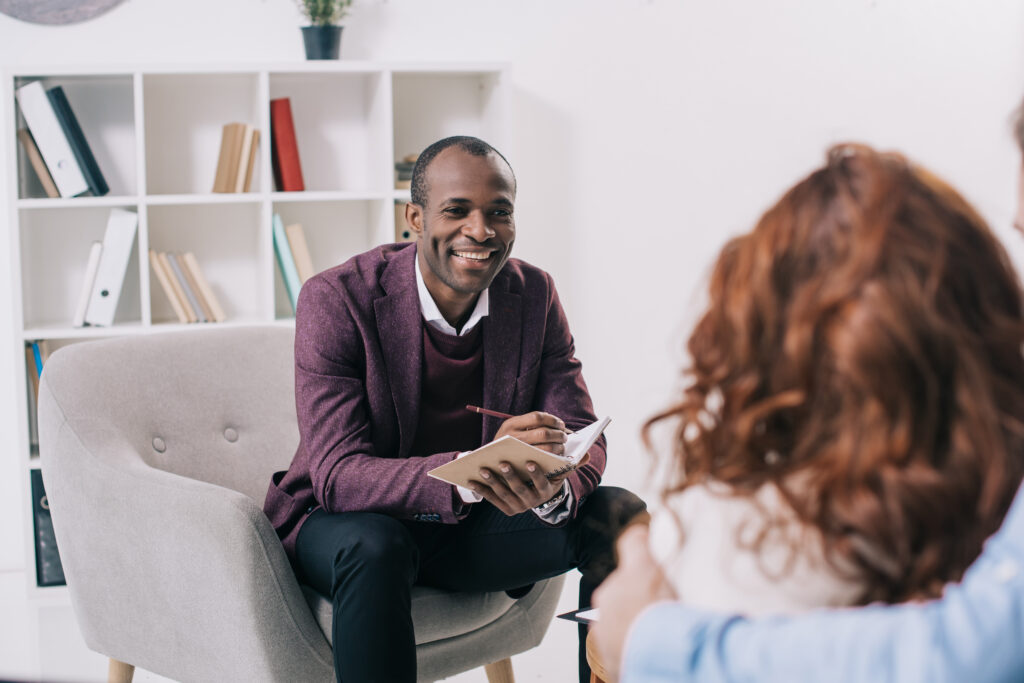 Smiling black psychiatrist talking to young couple